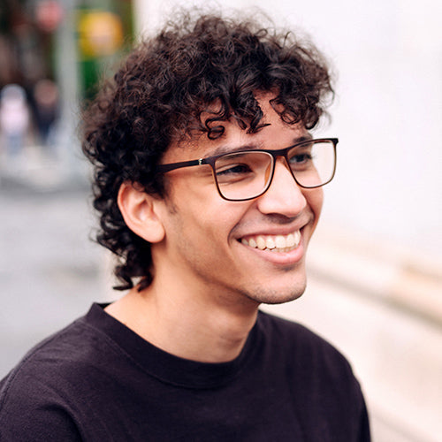A man wearing wide frame low power readers. 